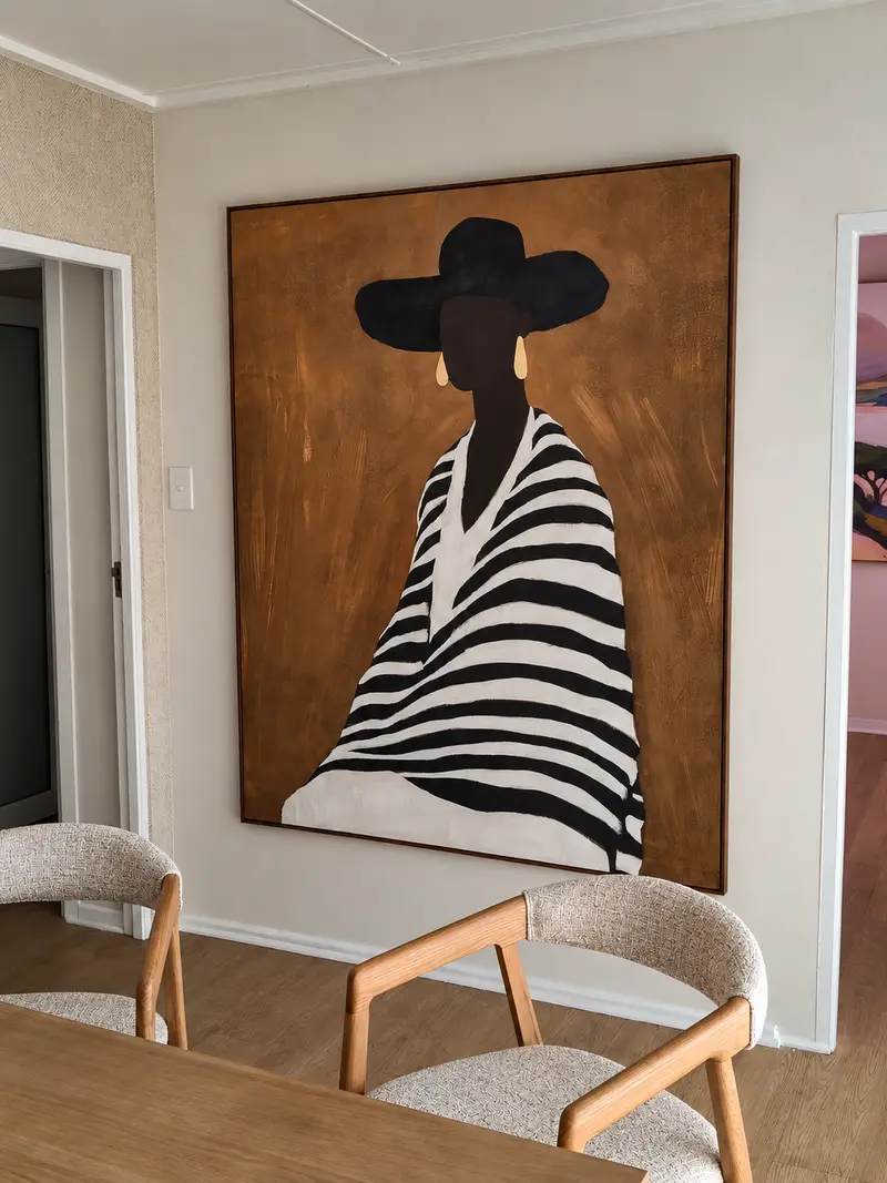 Large striped portrait artwork above oak dining chairs